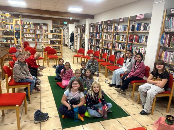 Kinder sitzen in der Bibliothek auf dem Boden und Sesseln