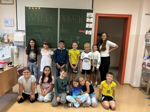 Kinder sitzen vor der Tafel und lachen 