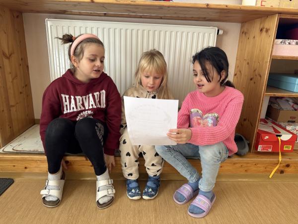 Drei Kinder die gemeinsam lesen.