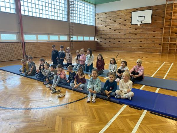 Kinder sitzen auf Matten im Turnsaal