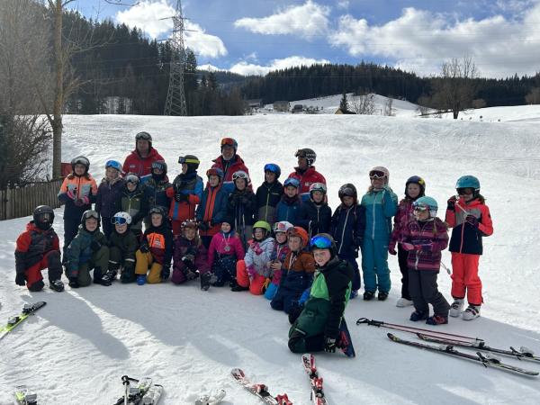 Die Kinder der VS Hönigsberg stehen als Gruppe vor der Piste und lachen in die Kamera