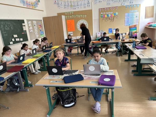 Kinder sitzen in einer Klasse vor Laptops